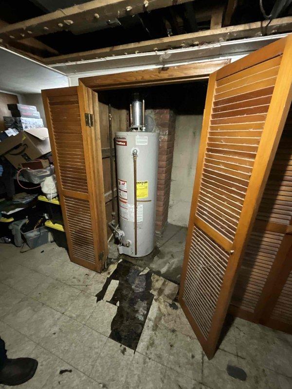 Conducted on-site assessment of residential water heater experiencing active leaking and complete heating failure. Unit is a standard atmospheric vent gas-fired water heater installed in basement utility closet with louvered door access. Inspection revealed visible water damage and staining on concrete floor beneath unit, indicating ongoing or recent leak from tank. Evaluated all plumbing connections, including copper supply lines, shut-off valves with blue handle, pressure relief valve, and flue vent system. Assessed condition of aging installation against deteriorated brick wall with exposed mortar joints. Documented compromised tank integrity and complete loss of heating function. Photographed existing installation configuration, piping layout, venting arrangement, and evidence of water damage for estimate preparation. Provided comprehensive evaluation for water heater replacement recommendation.