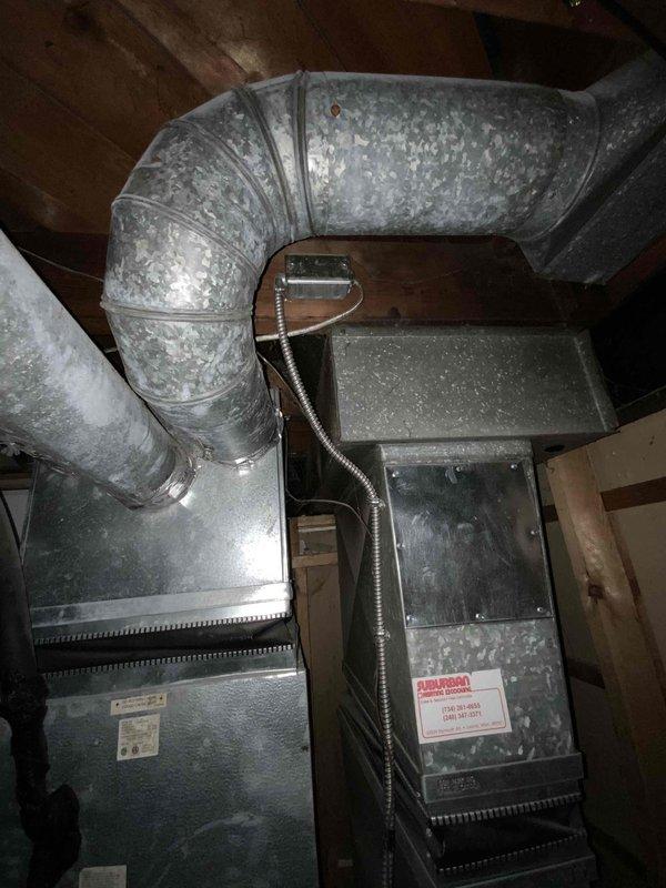 Provided comprehensive estimate for complete HVAC system replacement in basement location, including both furnace and air conditioning unit. Existing equipment is over 20 years old with non-functional air conditioning system, featuring natural gas furnace with aged galvanized metal exterior, flexible metal ductwork showing dust accumulation and discoloration, and standard residential configuration with exposed wooden structural elements. Assessed current installation layout, ductwork routing, electrical conduit connections, and equipment accessibility to develop replacement specifications for new high-efficiency heating and cooling system.