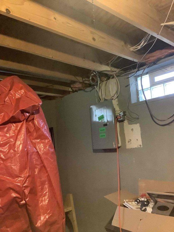 Conducted on-site assessment for electric vehicle charging station installation at detached garage and electrical panel upgrade requirements. Evaluated existing 100-amp basement electrical panel, photographed current configuration including panel condition, wiring routes through floor joists, and available pathways for new circuit installation to garage. Assessed electrical service capacity, panel space availability, and determined scope of work needed to accommodate Level 2 EV charger for incoming Chevrolet Equinox EV, including potential main service panel upgrade and dedicated circuit installation to detached garage structure.