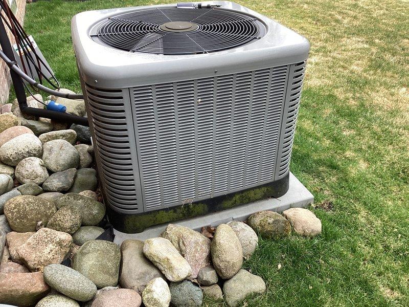 Completed routine maintenance on residential air conditioning condenser unit. Performed standard ACM service including inspection of condenser coils, fan operation, electrical connections, and refrigerant lines. Unit operational with algae/mildew growth noted on lower cabinet housing near concrete pad, typical of outdoor exposure in humid conditions.