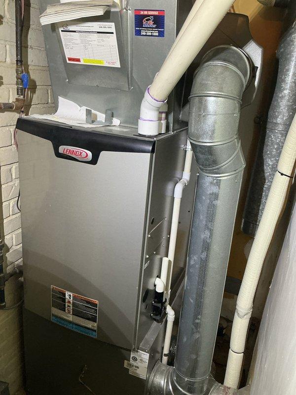 Completed annual cooling maintenance inspection on residential split HVAC system consisting of Lennox furnace with integrated air handler located in basement utility room and outdoor condensing unit. Performed comprehensive preventive maintenance protocol including visual inspection of indoor furnace cabinet, verified proper operation of blower assembly, and inspected all electrical connections at junction panel. Checked condensate drainage system including white PVC discharge lines for proper flow and absence of blockages. 

Inspected outdoor condensing unit positioned on concrete pad, verified structural integrity of mounting, and examined condenser coil fins for debris accumulation or damage. Assessed refrigerant lines, electrical connections, and overall unit operation. Confirmed adequate clearance around outdoor unit and proper airflow through protective grille. System operating within normal parameters with no immediate service needs identified. All manufacturer labels and safety