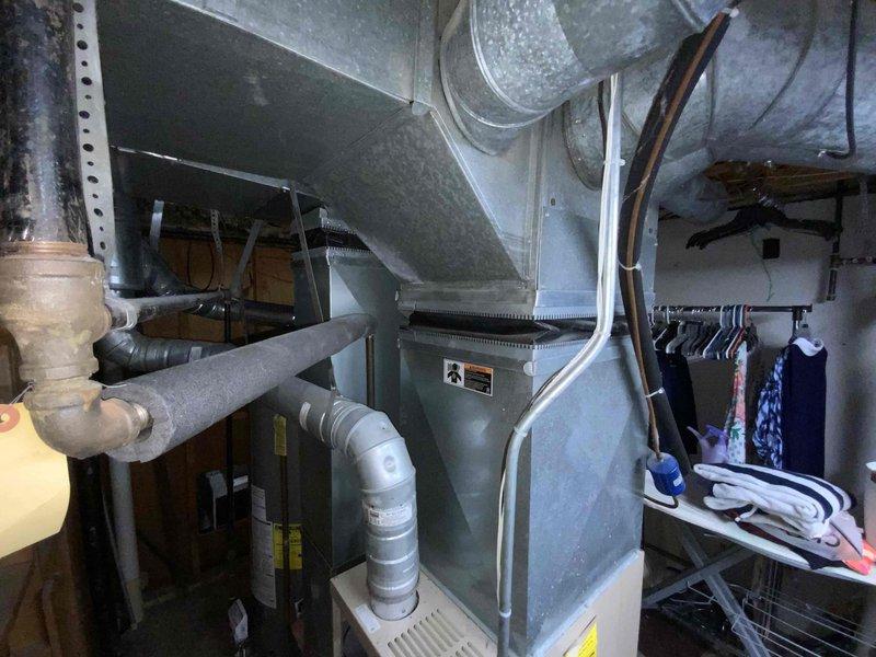 Provided comprehensive estimate for complete HVAC system replacement including both furnace and air conditioning unit in basement location. Assessed 23-year-old existing natural gas furnace and AC system, which is currently operational but nearing end of serviceable life with flame-out scheduled for March 2023. Documented existing equipment configuration, ductwork connections, plenum assembly, and installation space constraints through photographic documentation to develop accurate replacement proposal.