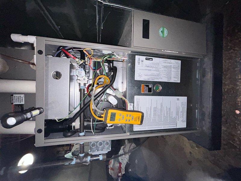 Completed annual heating maintenance on Lennox furnace system located in attic space. Performed comprehensive system inspection with access panel removed to evaluate internal components and electrical connections. Conducted diagnostic testing of electrical system using digital multimeter to verify proper voltage and amperage across all circuits and terminals. Inspected all wire connections including yellow, red, black, and white conductors at terminal points for secure connections and signs of wear. Verified all safety controls and limit switches functioning within manufacturer specifications. Examined condensate drainage system including white PVC piping for proper operation and drainage flow. Inspected ductwork connections and plenum assembly for secure attachment and proper sealing. Confirmed unit mounting and structural support adequate on concrete pad. Reviewed manufacturer specification labels and verified system operating within rated parameters. All components found operating n