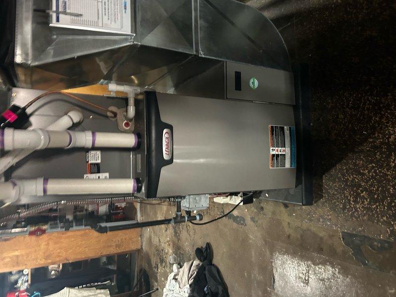 Completed annual heating maintenance on Lennox furnace system located in attic space. Performed comprehensive system inspection with access panel removed to evaluate internal components and electrical connections. Conducted diagnostic testing of electrical system using digital multimeter to verify proper voltage and amperage across all circuits and terminals. Inspected all wire connections including yellow, red, black, and white conductors at terminal points for secure connections and signs of wear. Verified all safety controls and limit switches functioning within manufacturer specifications. Examined condensate drainage system including white PVC piping for proper operation and drainage flow. Inspected ductwork connections and plenum assembly for secure attachment and proper sealing. Confirmed unit mounting and structural support adequate on concrete pad. Reviewed manufacturer specification labels and verified system operating within rated parameters. All components found operating n