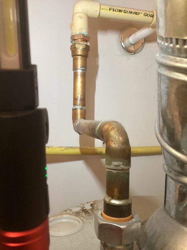 Responded to service call for water heater with small drip in basement. Upon inspection, identified corroded copper piping at water heater connection point showing significant oxidation and mineral buildup. The 2017 water heater exhibited leakage at the inlet plumbing assembly where deteriorated copper pipe connected to brass fittings. Documented existing conditions showing compromised pipe integrity with visible surface degradation and discoloration throughout the affected copper sections. Equipment is not covered under parts or labor warranty.