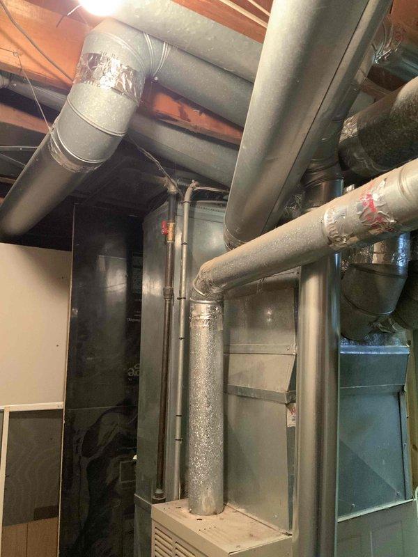 Conducted on-site assessment of existing HVAC system for residential replacement estimate. Inspected furnace and air conditioning equipment located in basement utility area, noting aging ductwork with deteriorated insulation and standard residential installation configuration. Documented current system conditions through photography, including furnace unit, ductwork layout, and associated mechanical components. Customer requested immediate replacement due to unknown equipment age and desire for new furnace and air conditioning system. Provided comprehensive evaluation of existing installation to prepare replacement proposal for complete heating and cooling system upgrade.
