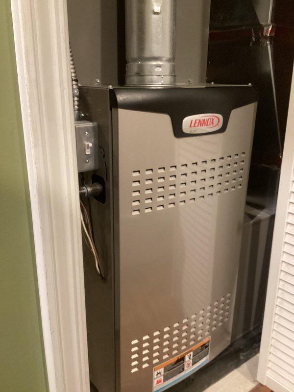 Completed annual furnace maintenance on Lennox brand heating unit installed in utility closet. Performed comprehensive tune-up inspection including removal of access panel to examine internal components, wiring connections, blower motor assembly, and control modules. Verified proper operation of pressure switch, examined all electrical connections including purple, blue, orange, green, and yellow wiring harnesses, and confirmed secure mounting of circuit boards and control systems. Inspected blower motor condition, orange condensate tubing, and copper refrigerant lines running along exterior of unit. All components found to be in good operational condition with no visible signs of wear, damage, or safety concerns. Unit operating within normal parameters with proper ventilation through perforated front panel. Reinstalled access panel and confirmed system functionality upon completion of maintenance protocol.