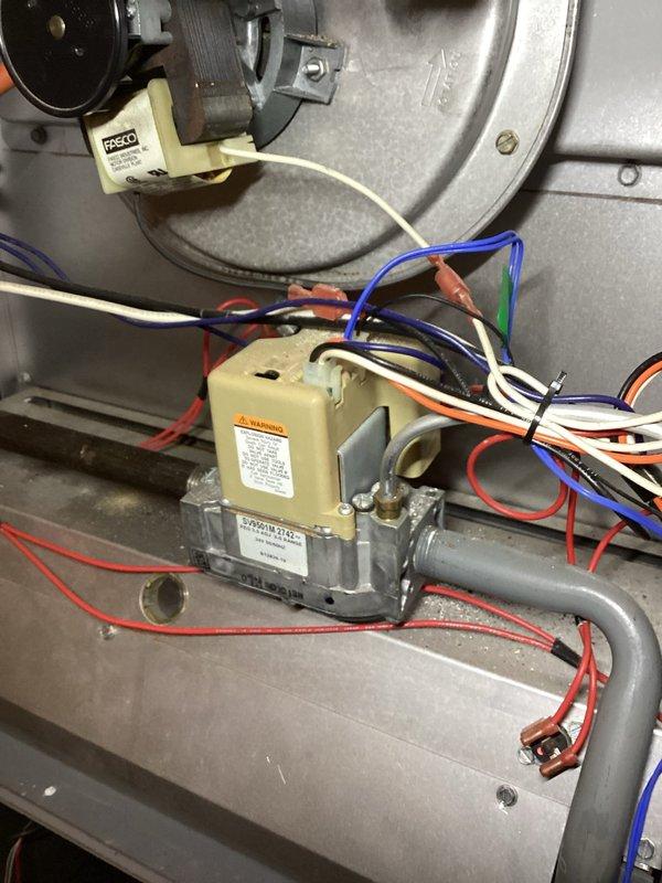 # HVAC Service Completed

Responded to no heat call on forced air furnace system. Upon arrival, confirmed heating system was not producing hot air. Performed visual inspection of furnace components including blower assembly and gas valve controls.

Inspected blower motor housing and found evidence of dust accumulation and age-related wear on metal surfaces. Examined gas valve assembly with multi-wire connections including safety and control wiring. All electrical connections to gas valve were intact with proper wire routing through housing. Verified blower motor mounting hardware and access panel security.

Photographed gas valve assembly showing Honeywell control valve with connected wiring harnesses and gas piping. Documented blower housing condition including mounting brackets and fastener placement for service records. System components showed normal operational wear consistent with equipment age.