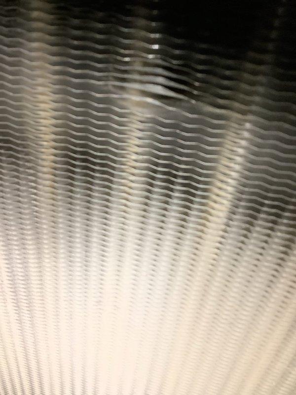 Responded to no heat call for furnace system located in basement, approximately 2015 model. Upon inspection, discovered significant moisture condensation and frost accumulation on heat exchanger surfaces and adjacent ductwork components. Examined heat exchanger fins, which showed evidence of abnormal condensation patterns indicating potential airflow restriction or combustion issues. Documented condition of corrugated metal heat exchanger sections and metallic ductwork connections. Moisture buildup on system components suggests possible secondary heat exchanger drainage blockage, restricted airflow due to dirty filter or blower issues, or condensate system malfunction requiring further diagnostic evaluation and repair to restore proper heating operation.