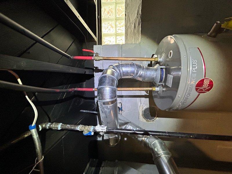 Responded to no heat call for 4-year-old forced air furnace system. Upon arrival, discovered significant water damage on basement floor near HVAC equipment location, with visible pooling and concrete deterioration around floor drain area. Investigation revealed water heater in attic space above furnace area with multiple plumbing connections showing signs of moisture. Determined that water intrusion from leaking water heater or associated plumbing had compromised furnace electrical components and safety controls. Documented extensive water damage with photographs showing affected concrete surfaces and standing water conditions. Advised immediate attention to water heater leak source and water mitigation before furnace system could be safely restored to operation, as moisture presents electrical hazard and potential for further equipment damage.