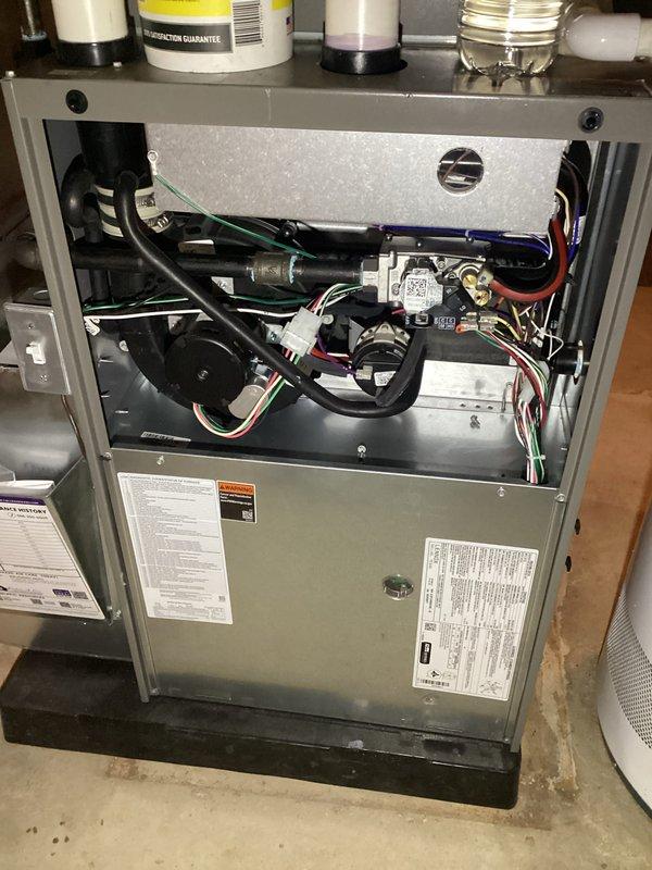 Completed annual furnace maintenance and tune-up on residential heating system. Performed comprehensive inspection of all internal components including blower motor assembly, gas valve, control board, and electrical connections. Removed upper access panel to access and evaluate burner assembly, heat exchanger, and ignition system. Verified proper gas combustion with blue flame pattern across all burner ports, indicating optimal air-to-fuel ratio. Inspected all wiring connections including ground, neutral, and control circuits for secure termination and proper routing. Examined blower motor operation and mounting integrity. Checked gas supply lines and connections for leaks and proper installation. Verified all safety labels and manufacturer specifications posted on unit cabinet. Documented furnace condition with photographic evidence showing internal components and active burner operation. System operational and functioning within normal parameters upon completion of maintenance proced