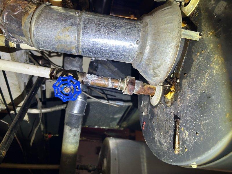 Responded to emergency water heater repair call for issue that had just developed in residential property. Upon inspection, identified problem with tanked water heater system located in basement utility area. Examined main water heater unit and associated plumbing connections, including pressure relief valve assembly, shut-off valves, and supply line connections. Noted aging galvanized components with surface oxidation and copper piping showing corrosion and mineral deposits. Evaluated blue-handled shut-off valve, pressure gauge functionality, and various brass fittings throughout the system. Addressed the immediate malfunction to restore hot water service to the residence. Tested system operation following repairs to ensure proper pressure levels and verify no leaks at connection points. Documented equipment condition and captured photos of the installation for service records.