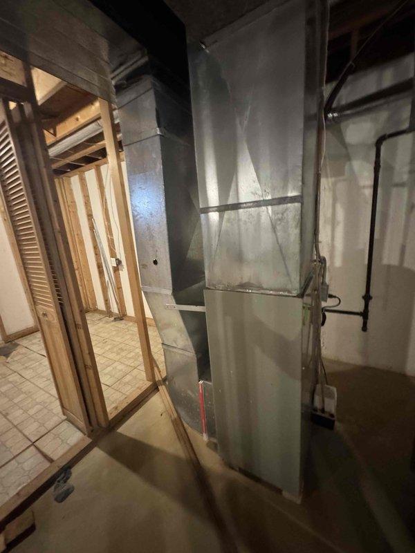 Provided estimate for complete HVAC system replacement in basement location, including natural gas furnace and air conditioning unit. Current 25-year-old AC system is non-operational while existing furnace remains functional. Assessment included evaluation of existing ductwork infrastructure and equipment accessibility in unfinished basement space with exposed framing and concrete flooring.
