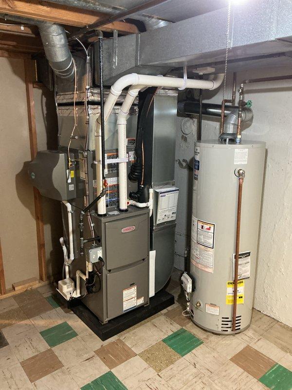 Completed full HVAC system installation including a 70,000 BTU furnace with humidifier and liner, 2-ton rear-discharge air conditioning unit, and hot water heater replacement in basement utility space. All equipment mounted on appropriate platforms with PVC venting routed through ceiling joists, copper supply lines connected, and condensate drainage properly configured. Mechanical and electrical permits obtained prior to installation, all units tested and operational upon completion with reconnection of existing ductwork system.