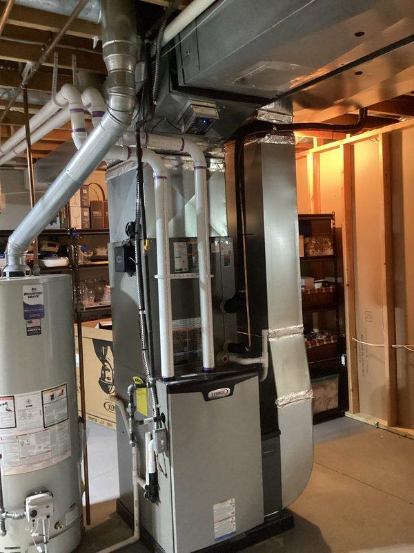 Completed full HVAC system installation in basement utility area including 90,000 BTU high-efficiency furnace with humidifier, 3-ton air conditioning unit with rear placement, and residential water heater. All ductwork, ventilation piping, and electrical connections were installed per code specifications. PVC condensate and exhaust venting routed through ceiling joists with proper pitch and support. Sheet metal supply and return ductwork fabricated and connected to furnace plenum. Flexible duct transitions installed where required for equipment connections. Water heater positioned adjacent to furnace with appropriate clearances for service access. All gas piping, water lines, and drain connections completed and tested for leaks. Air conditioning refrigerant lines run to outdoor condenser unit and system charged to manufacturer specifications. Thermostat wiring pulled and connected to new furnace control board. Humidifier integrated into supply plenum with water line and drain installed