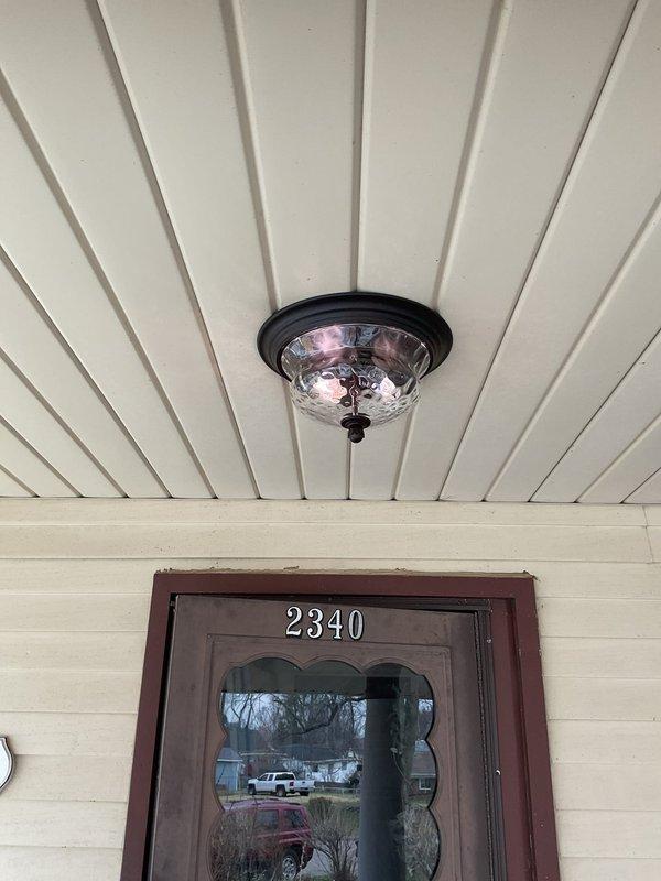 Replaced deteriorated outdoor porch light fixture with new flush-mount ceiling fixture featuring bronze finish and textured glass shade. Removed heavily corroded wall-mounted fixture showing significant weather damage and rust accumulation, disconnected existing wiring, and installed updated fixture to ceiling mount position for improved aesthetics and functionality. Additionally, repaired ceiling fan pull chain mechanism that had been improperly installed during previous replacement attempt, restoring full operational control to the fan unit.