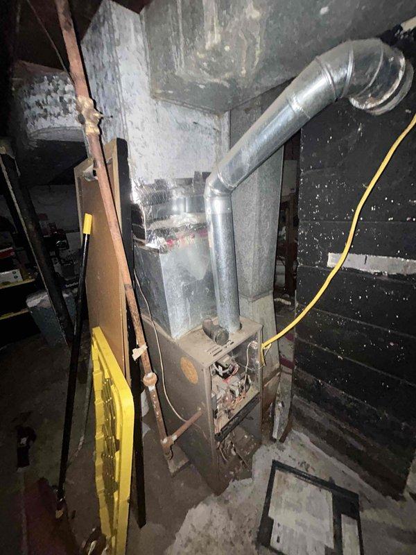 Conducted residential furnace replacement estimate for a seven-year-old heating system showing visible signs of age and deterioration. Documented existing equipment condition, including worn exterior casing and aging infrastructure within the utility space. Photographed electrical panel configuration, existing ductwork connections, and current furnace installation to assess replacement requirements and ensure proper sizing for new equipment installation.