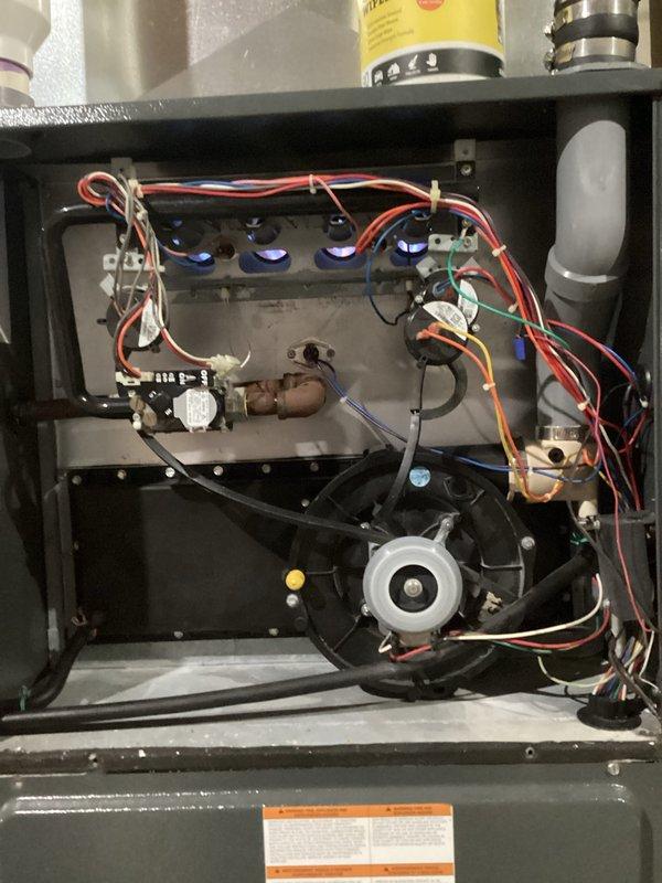 Completed annual HVAC maintenance on air handling unit, including system inspection, filter replacement, and verification of blower assembly operation. Accessed furnace cabinet to inspect electrical connections, gas valve assembly, flame sensors, and blower motor components, confirming all systems functioning properly. All four flame sensors displayed proper blue indicator lights, wiring connections were secure, and blower wheel showed normal wear patterns with adequate airflow performance.