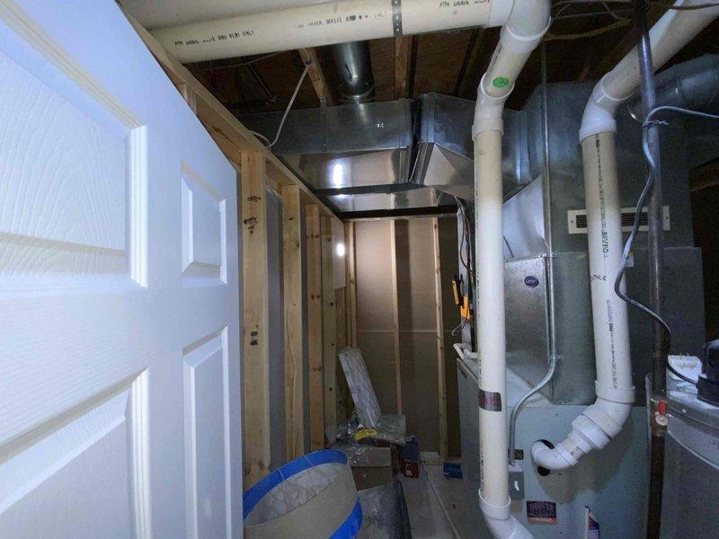 Completed estimate for replacement of 20-year-old non-functional natural gas furnace and air conditioning system located in basement utility area. Assessed existing HVAC infrastructure including ductwork, electrical service, and gas line connections in unfinished basement space with exposed framing. Provided quote for new furnace and AC unit installation under buy-one-get-one promotion, documenting current equipment conditions and required modifications to accommodate new systems.