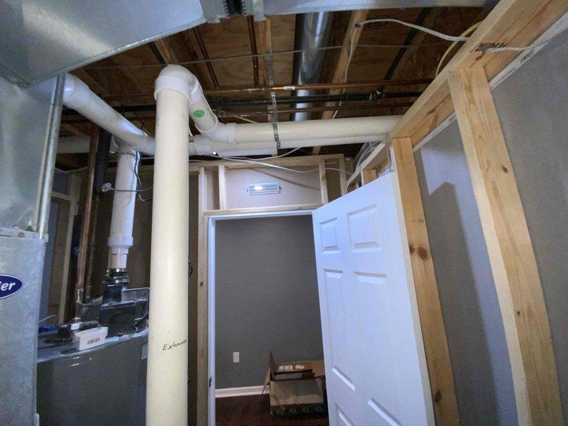 Completed estimate for replacement of 20-year-old non-functional natural gas furnace and air conditioning system located in basement utility area. Assessed existing HVAC infrastructure including ductwork, electrical service, and gas line connections in unfinished basement space with exposed framing. Provided quote for new furnace and AC unit installation under buy-one-get-one promotion, documenting current equipment conditions and required modifications to accommodate new systems.