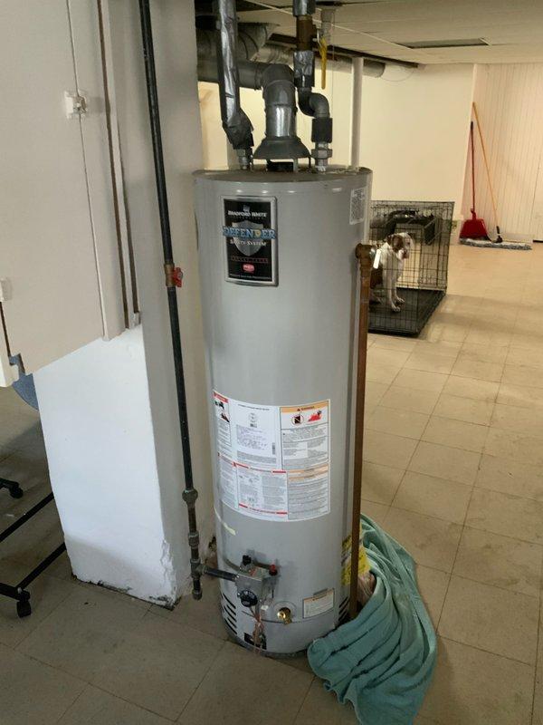 Conducted on-site evaluation of existing water heater installation in basement utility area to provide replacement estimate. Inspected current cylindrical tank-style water heater with top-mounted connections, pressure relief valve, and flexible supply lines. Assessed venting configuration to determine whether unit operates as power vent or natural draft system. Documented electrical service panels labeled for upper and lower level circuits to verify power supply compatibility for potential replacement unit. Photographed existing installation including plumbing connections, floor clearances, and surrounding workspace access for accurate equipment sizing and installation planning.