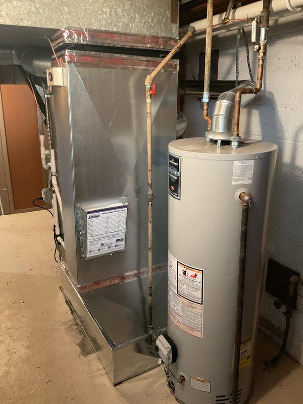 Completed full HVAC system installation including a 70,000 BTU furnace and 2-ton air conditioning unit. Furnace installed in basement utility area with proper venting and ductwork connections. AC condenser positioned on exterior left side of building in alcove area formed by brick walls. Electrical disconnect and junction boxes mounted to exterior wall with conduit run to condenser unit. All mechanical, electrical, and HVAC permits obtained prior to installation. System reconnected to existing infrastructure and tested for proper operation upon completion.