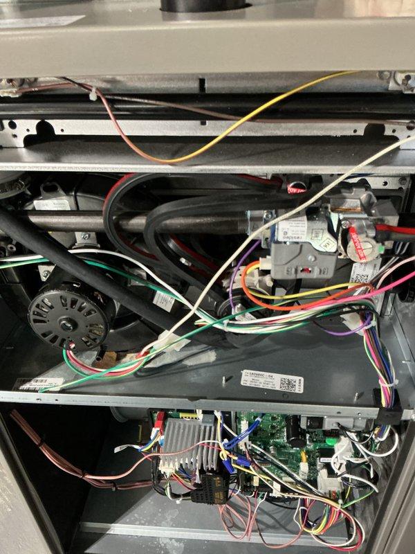 Completed comprehensive annual furnace maintenance and tune-up on residential heating system. Performed thorough inspection of all internal components including blower motor assembly, gas valve, control board, electrical connections, and wiring harnesses. Verified proper operation of all safety controls, cleaned burner assembly, checked gas pressure and combustion efficiency, inspected heat exchanger for cracks or deterioration, and tested limit switches and flame sensor. All electrical connections were examined and secured, capacitor tested within normal parameters, and blower wheel inspected for debris. System operational testing confirmed furnace is functioning properly with no issues detected. Unit photographed for service records showing internal components and control board condition.