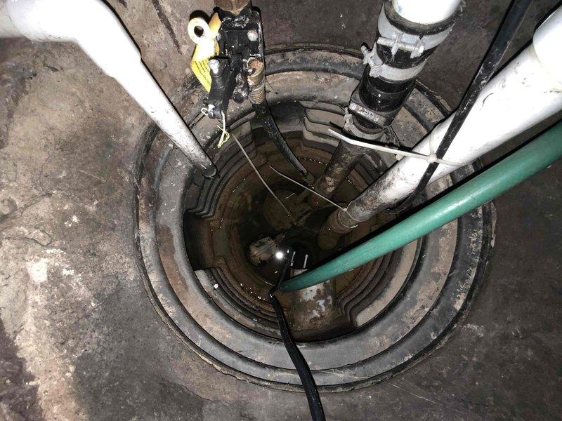 Completed assessment and estimate for sump pump replacement in 43-year-old residential property. Inspected existing submersible sump pump system with floating switch mechanism located in circular ridged plastic basin. Documented deteriorating conditions including standing water accumulation, aged plumbing connections with multiple PVC and flexible drainage lines, and pump equipment showing signs of extended service life. Photographed entire sump pit assembly, discharge piping configuration, electrical wiring routing, and surrounding basement infrastructure to provide comprehensive documentation for replacement proposal.