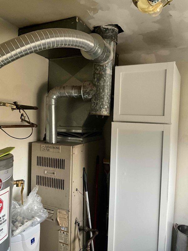 Provided estimate for replacement of 15-year-old furnace and air conditioning system currently located in laundry room utility closet. Existing Armstrong furnace and associated ductwork evaluated for replacement specifications. Noted presence of mold or dark discoloration on structural beam near ductwork connection that may require remediation during installation.