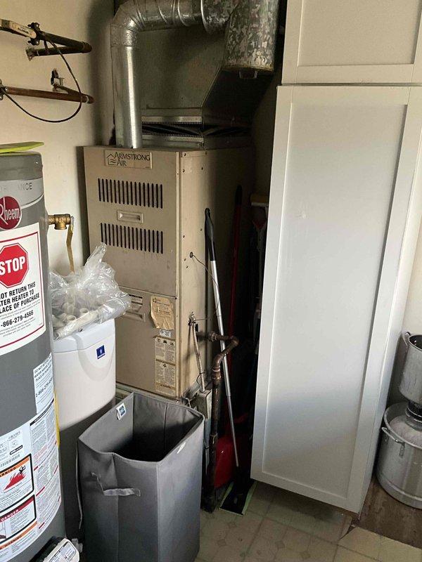 Provided estimate for replacement of 15-year-old furnace and air conditioning system currently located in laundry room utility closet. Existing Armstrong furnace and associated ductwork evaluated for replacement specifications. Noted presence of mold or dark discoloration on structural beam near ductwork connection that may require remediation during installation.