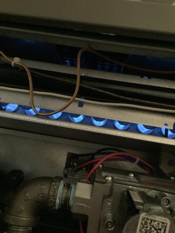 Completed comprehensive Air Care Heating maintenance on gas furnace system. Performed visual inspection of all internal components including burner assembly, gas valve, ignition system, and blower motor. Verified proper flame characteristics with blue flames burning consistently across burner assembly, confirmed gas valve operation with all electrical connections secure, and documented system condition with photos showing normal operational status. All components functioning within manufacturer specifications with no immediate repairs required.