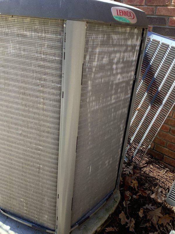 Completed annual preventive maintenance on Lennox air conditioning condensing unit. Inspected condenser coil and found moderate dirt and debris accumulation on exterior fins. Cleared leaves and debris from around unit base and perimeter. Evaluated protective grille screens for proper airflow and noted environmental buildup consistent with outdoor exposure. Verified condenser coil fins remain intact with proper spacing throughout. Unit operational and positioned on stable concrete pad against brick wall exterior. All components accessible for routine maintenance procedures.