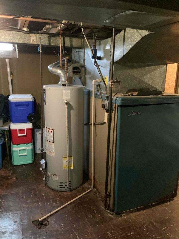 Conducted comprehensive assessment of 71-year-old Luxaire natural gas furnace located in basement utility area. Evaluated existing heating system configuration, ductwork connections, venting arrangement, and overall equipment condition to provide replacement estimate for aging HVAC equipment. Documented current installation including water heater proximity, copper piping layout, and available space requirements for new system installation.