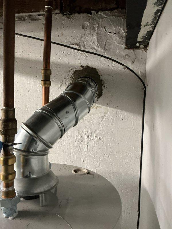 Completed callback for chimney liner installation on water heater system. Installed metallic B-vent ductwork with proper elbow joint configuration through wall penetration, ensuring secure connection from appliance flue collar to exterior termination point. Verified proper venting clearances, sealed all joints, and confirmed draft operation meets manufacturer specifications and local building codes.