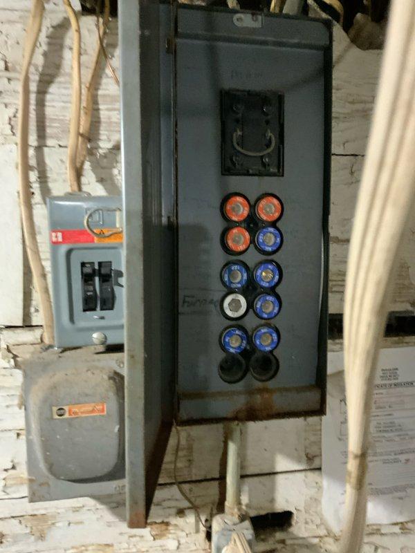 Conducted comprehensive assessment of 32-year-old residential furnace system for replacement estimate. Documented existing HVAC equipment configuration including furnace unit, ductwork connections, and electrical service panel in basement utility area. Photographed current system installation, noting beige cabinet-style furnace with digital display, gray ductwork routing, electrical panel with fuse holders, and overall mechanical room layout to provide accurate replacement specifications and equipment sizing recommendations.