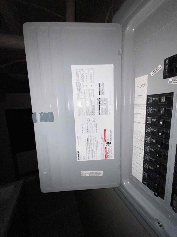 Conducted on-site assessment for central air conditioning system replacement at residential property. Inspected existing outdoor condensing unit, refrigerant line set, electrical disconnect, and associated components along exterior wall. Documented current system configuration including condenser placement, electrical service panel with circuit breakers, and refrigerant piping routing. Evaluated installation area conditions, noting exterior siding condition and ground surface characteristics that may impact replacement installation. Photographed existing equipment and electrical infrastructure to support replacement system specifications and quote preparation.