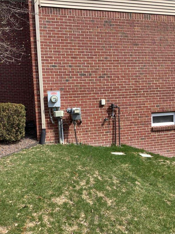 Completed electrical estimate for new whole home Generac generator installation at residential property. Assessed existing electrical panel containing dual columns of circuit breakers and evaluated exterior utility connections including electric meter, gas piping, and conduit routing along brick exterior wall. Determined specifications and requirements for generator integration with current electrical system to provide comprehensive backup power solution for the home.