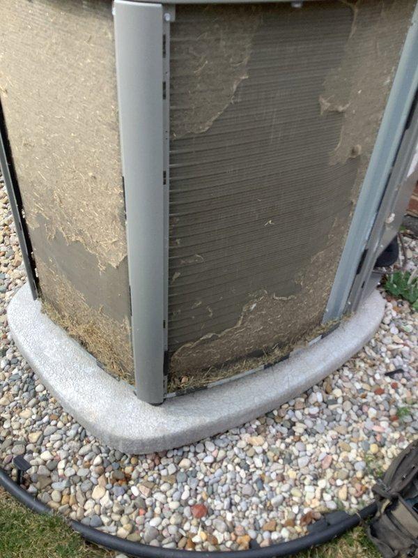 Completed scheduled maintenance on outdoor air handling condenser unit. Performed standard AHC maintenance protocol including inspection of exterior panels, coil surfaces, and mounting pad condition. Unit showed typical weathering and debris accumulation on exterior surfaces and coil fins from environmental exposure. Documented equipment condition with photos showing gravel bed installation, concrete pad, and protective mesh screening with age-appropriate wear patterns.