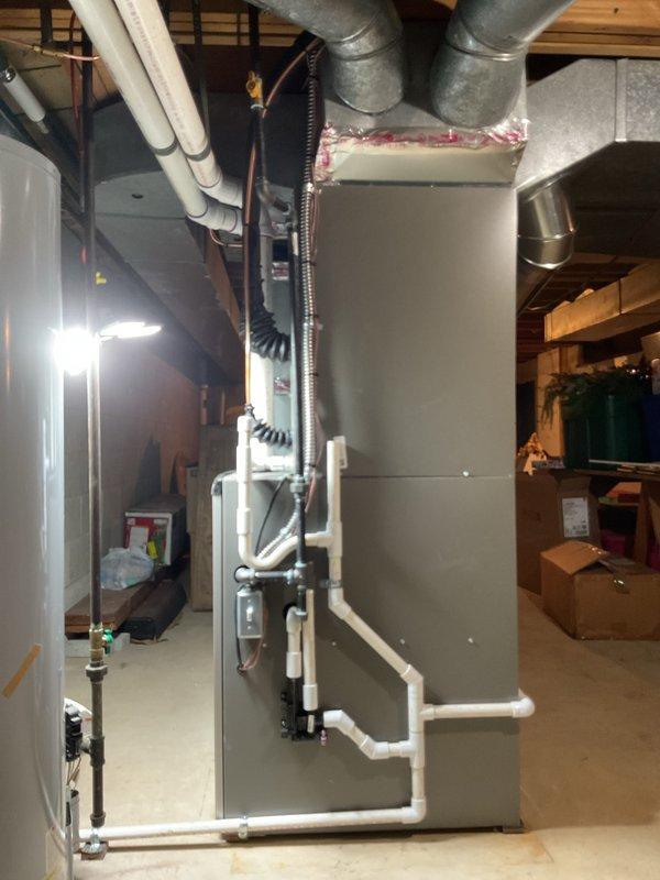 Completed full HVAC system installation including 90,000 BTU gas furnace with left-side configuration, 3.5 ton air conditioning condenser unit, and whole-home humidifier. Installed outdoor AC condenser on concrete pad against brick exterior with proper refrigerant line routing and secure mounting brackets. Ran new dedicated electrical circuit and installed disconnect box to meet code requirements. Positioned furnace/air handler in basement utility area with proper clearances and connected to existing ductwork infrastructure. Installed white PVC condensate drainage lines and venting per manufacturer specifications. Secured all refrigerant lines, electrical conduit, and mechanical connections. Verified system startup, checked refrigerant charge levels, tested all safety controls, and confirmed proper airflow throughout duct system. All mechanical and electrical permits obtained and installation completed to code compliance standards.