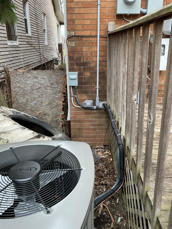 Completed installation of 2.5-ton Lennox air conditioning system with matching evaporator coil at residential property. Installed outdoor condenser unit on ground pad in side yard area adjacent to brick exterior wall. Ran refrigerant linesets and electrical conduit along exterior brick wall to connect outdoor unit to indoor coil. Installed electrical disconnect box and completed electrical connections to existing 100-amp service panel. Secured all refrigerant lines and electrical conduit to brick wall with proper mounting straps. Verified all electrical connections meet code requirements for mechanical and electrical permits. System installation completed per specifications with rear placement configuration. All components properly mounted and secured for operational readiness.