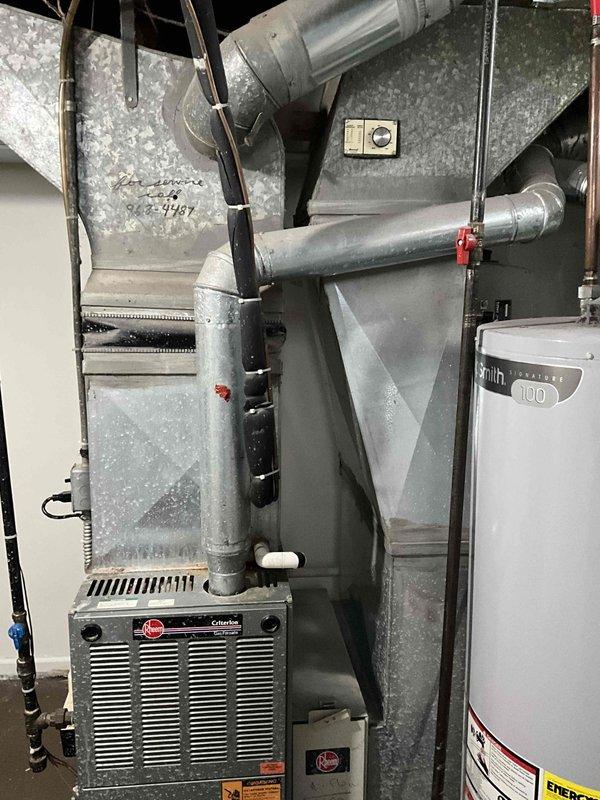 Conducted comprehensive assessment of existing 20+ year old Rheem Criterion furnace and complete HVAC system at rental property requiring immediate replacement. Documented current system configuration including furnace unit, galvanized ductwork network, gas line connections, and adjacent water heater in basement utility area. Accessed property using lockbox code and photographed all equipment for estimate preparation, noting system age and need for full replacement installation.