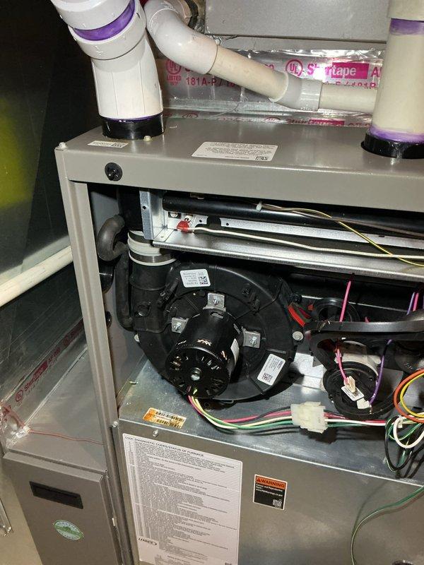 Responded to service call for HVAC system exhaust leak covered under warranty. Upon inspection, identified compromised exhaust piping requiring replacement. Accessed unit, documented existing configuration including blower motor assembly, electrical connections, and current PVC drainage system with purple-primed joints. Determined complete exhaust repipe necessary to resolve leak issue. Parts ordered through supply house under warranty coverage for scheduled installation.
