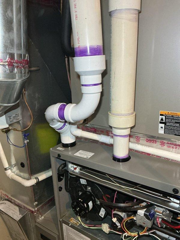 Responded to service call for HVAC system exhaust leak covered under warranty. Upon inspection, identified compromised exhaust piping requiring replacement. Accessed unit, documented existing configuration including blower motor assembly, electrical connections, and current PVC drainage system with purple-primed joints. Determined complete exhaust repipe necessary to resolve leak issue. Parts ordered through supply house under warranty coverage for scheduled installation.