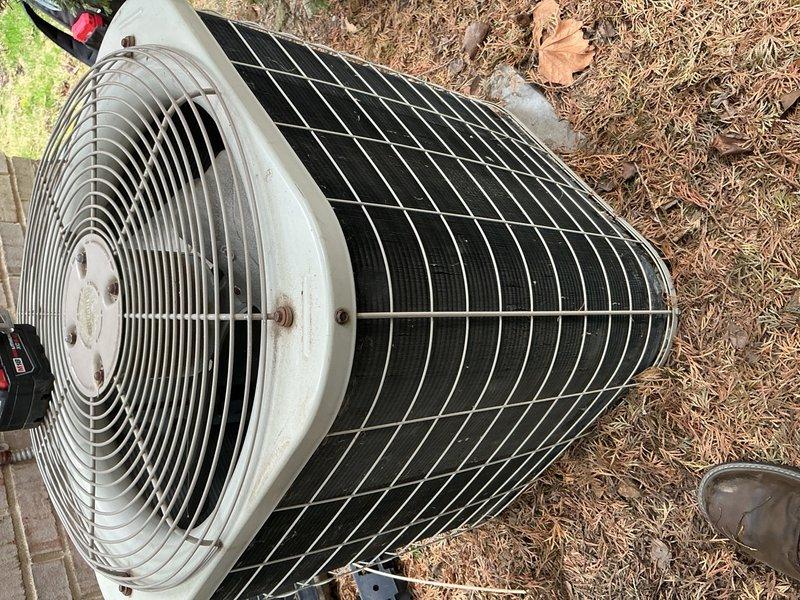 Completed annual preventive maintenance on outdoor cylindrical condenser unit. Inspected fan assembly, verified fan blade operation through protective grille, and examined heat exchanger coils for damage or deterioration. Cleaned debris from surrounding area including pine needles and leaf litter. Verified protective wire guard integrity and checked all mounting hardware and fasteners for security. Unit operational with no immediate repairs required.