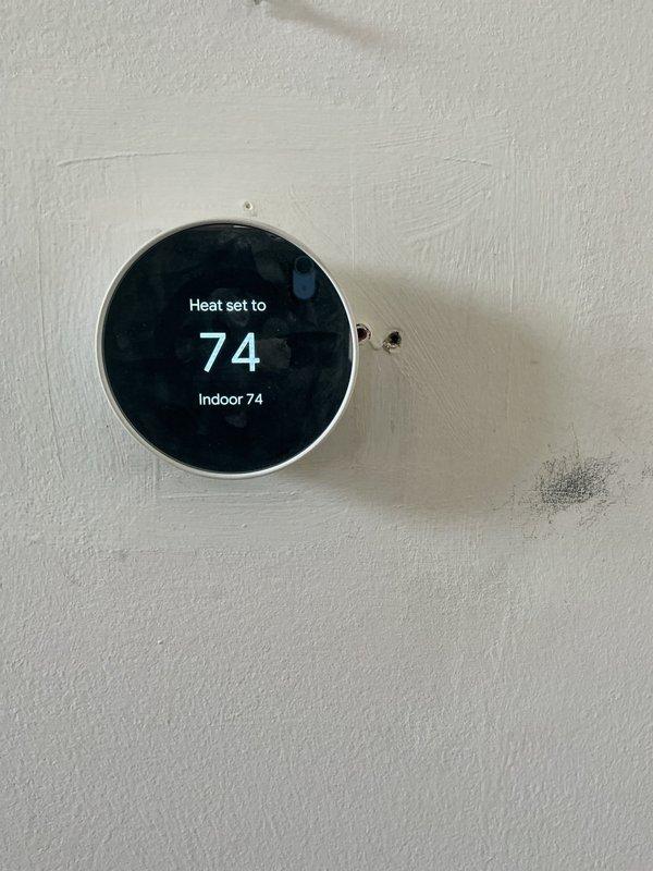 Completed annual HVAC maintenance inspection including replacement of furnace filter and humidifier pad as part of recurring Air Care Heating and Cooling service. Performed electrical diagnostics using multimeter to verify system operation, confirmed proper voltage readings at .548V on tested component, and inspected internal wiring connections and blower assembly. Verified thermostat functionality with system maintaining setpoint at 74°F and displaying accurate indoor temperature reading.