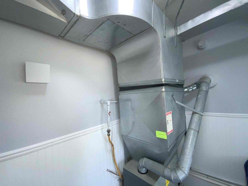 Conducted on-site evaluation for central air conditioning installation in residential property with no existing central air system. Assessed existing HVAC infrastructure including furnace/air handler unit, ductwork configuration, and mechanical space in basement utility room. Evaluated gray metal ductwork system, flexible ducting connections, and vertical cylindrical duct routing for compatibility with proposed AC system integration. Documented current equipment setup, including air handler positioning, duct runs along ceiling, and available space for outdoor condenser unit placement. Photographed existing installation to support estimate preparation for complete central air conditioning system addition scheduled for spring installation.