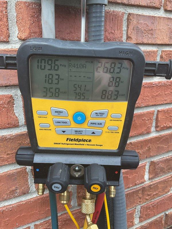 Completed ACM3/312-5 maintenance on residential air conditioning system. Performed refrigerant pressure and temperature diagnostics using digital manifold gauge set, recording low-side pressure of 109.6 PSIG and high-side pressure of 268.7 PSIG with corresponding saturation temperatures. Inspected outdoor condenser unit positioned on concrete pad, verified proper airflow through coil fins, and confirmed fan grille protection in place. Unit operating within normal parameters with no refrigerant leaks detected. All system components functional and equipment ready for continued service.