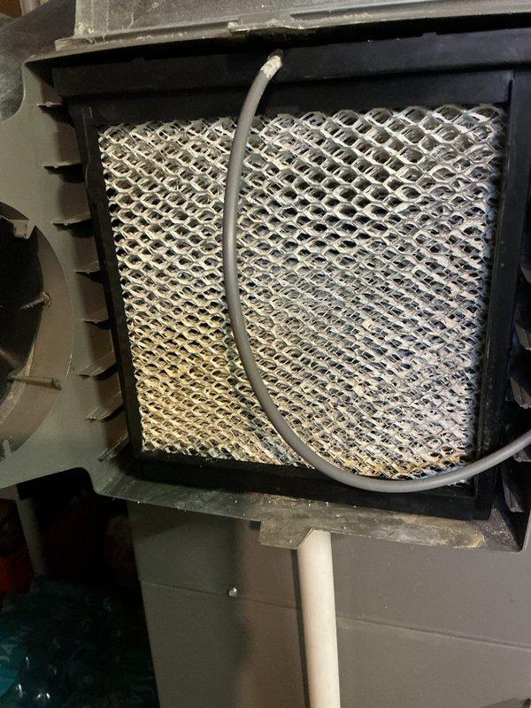 Completed annual cooling maintenance on residential split system HVAC unit. Inspected indoor evaporator coil assembly, noting moderate dust accumulation with visible discoloration on coil surface requiring monitoring for future cleaning. Verified blower compartment accessibility and checked flexible condensate drain line routing. Evaluated outdoor condensing unit positioned on concrete pad, inspecting finned coil condition and refrigerant line insulation integrity. Documented equipment condition through photographic records for maintenance history. All components operational at time of service completion.