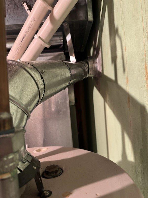 Provided estimate for replacement of non-functioning standard natural draft water heater in residential property. Assessed existing water heater installation including venting configuration, supply and discharge piping penetrations through utility area walls, and connection points. Documented current plumbing infrastructure with natural draft venting system to determine appropriate replacement specifications and installation requirements.