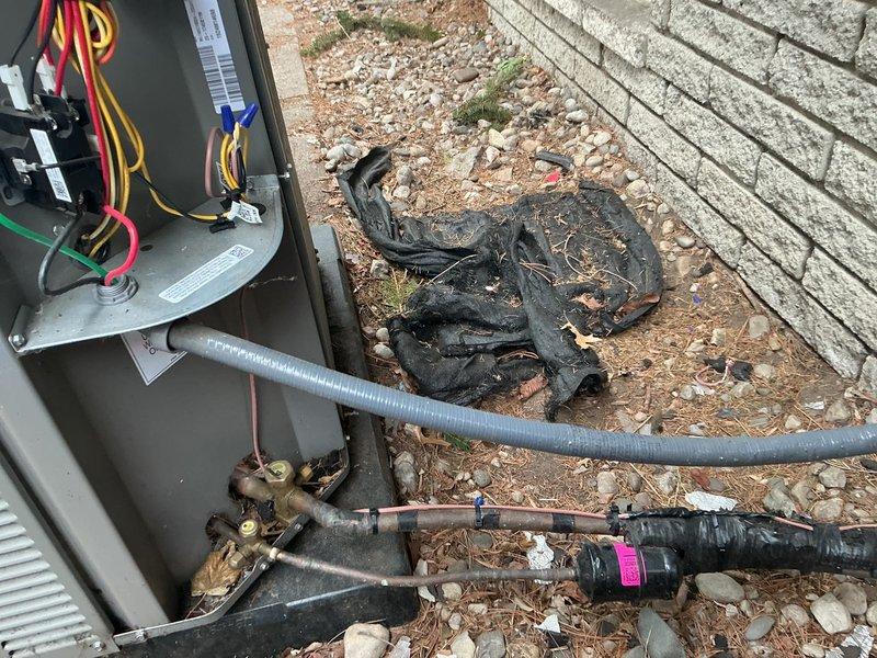 # HVAC Service Report

Responded to no-cooling complaint on one-year-old air conditioning system. Upon arrival, discovered severe electrical failure at outdoor unit with extensive heat damage to wiring and electrical components. Found melted and charred wiring harness, indicating catastrophic electrical short or overload condition. Inspected electrical panel box and internal connections, noting damaged conductors and compromised circuit protection components. Evaluated refrigerant line connections showing corrosion at fittings, though refrigerant circuit integrity remained intact. Documented extensive thermal damage to electrical infrastructure requiring complete replacement of affected wiring, connectors, and control components. System remains under parts and labor warranty coverage. Unit secured and made safe pending parts procurement and complete electrical system restoration.